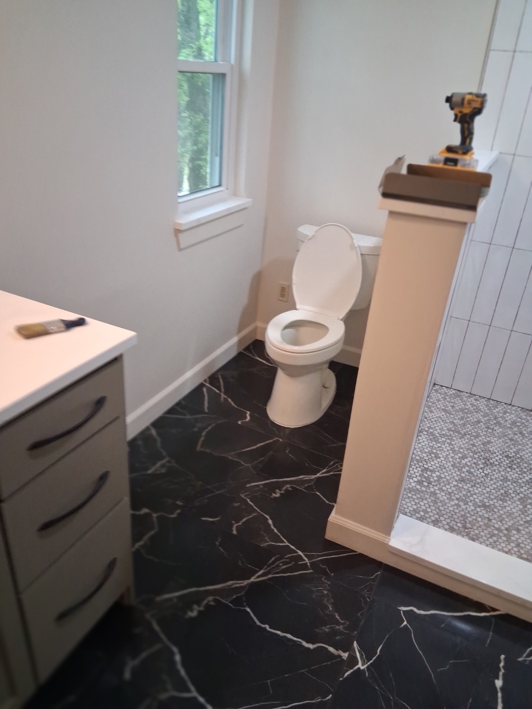 Bathroom overview showing black marble tile floor, vanity, and shower