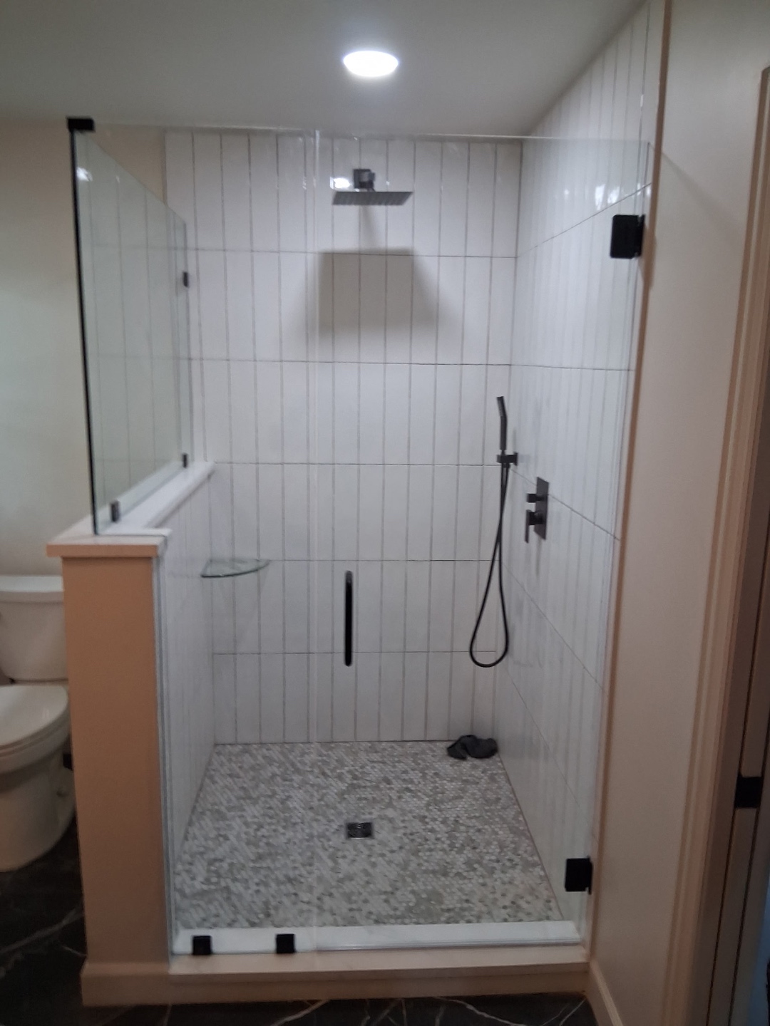 Finished bathroom — frameless glass shower with pebble floor, recessed lighting